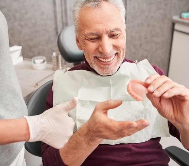 Senior dental patient looking at a denture