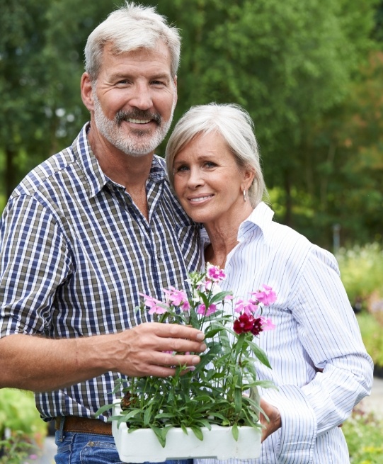 Senior man and woman holding box of flowers outdoors
