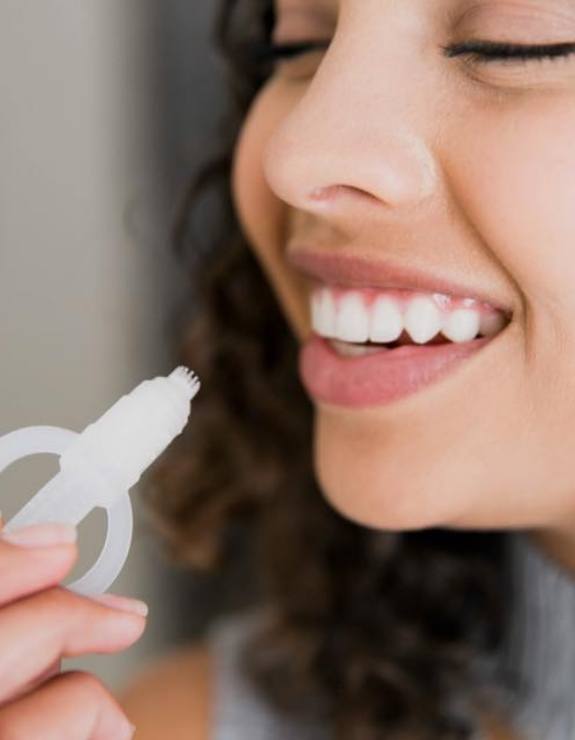 Woman using take home teeth whitening kit