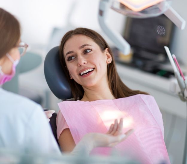 Woman in dental chair talking to dentist