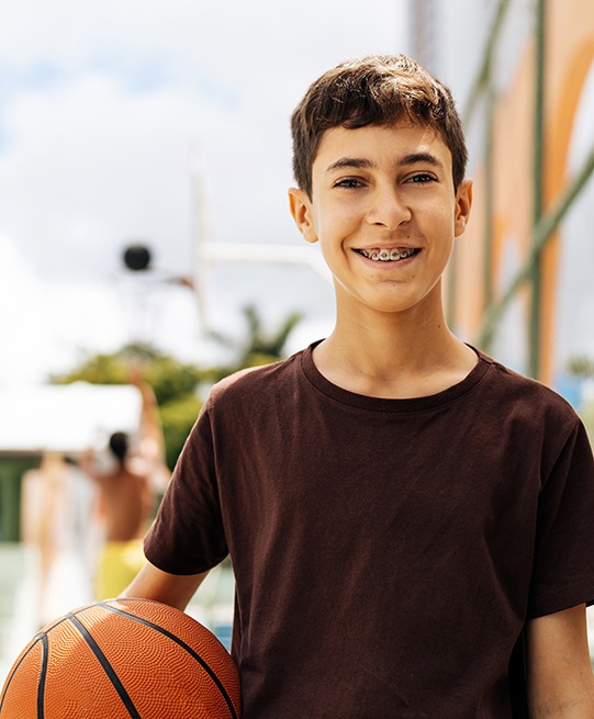 child smiling while holding basketball 