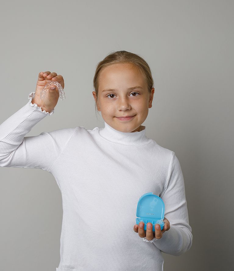 young boy smiling and holding mouthguard