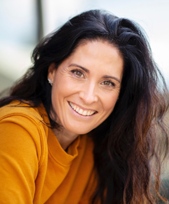 Woman with long dark hair smiling with dental bridges in Arlington Heights