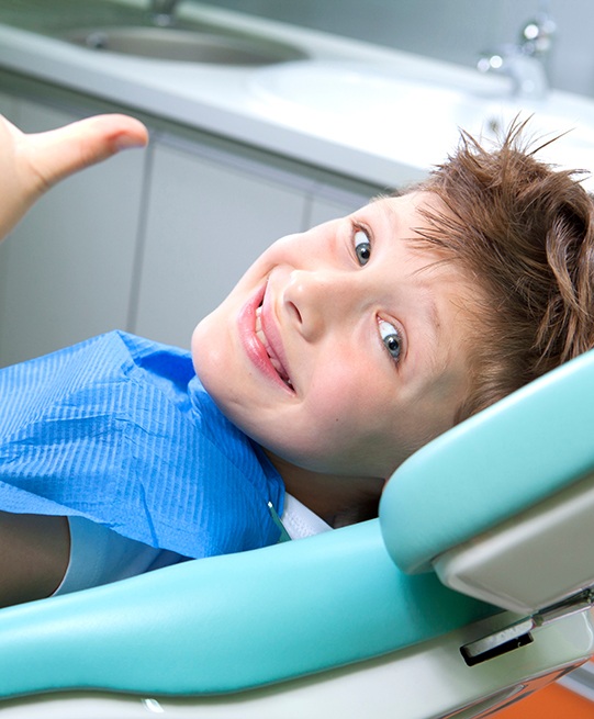 child smiling while giving thumbs up