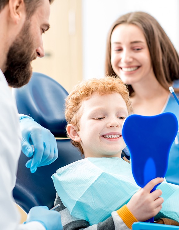 Child looking at smile in mirror after dental sealants