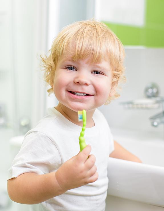 Small child brushing teeth at sink