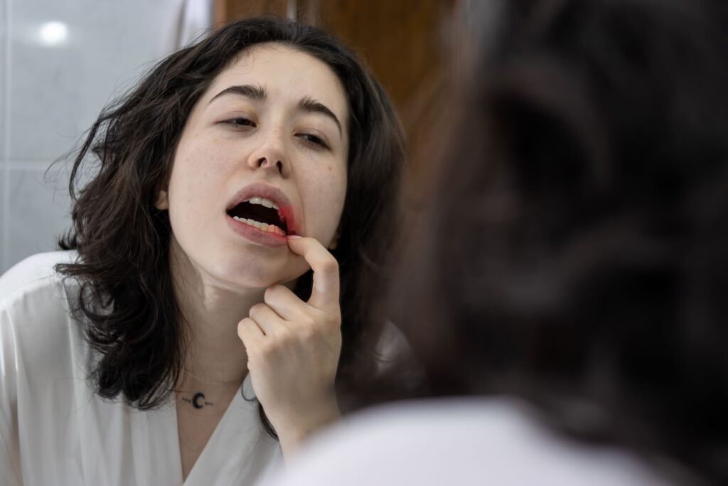 A woman looking at her gums in the mirror.